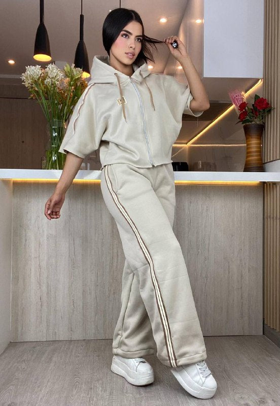 Mujer con conjunto beige de pantalón y chaqueta deportiva con rayas, en cocina moderna