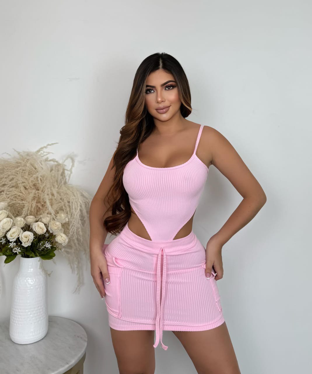 Mujer con conjunto de body y falda rosa, moda femenina juvenil, fondo blanco elegante