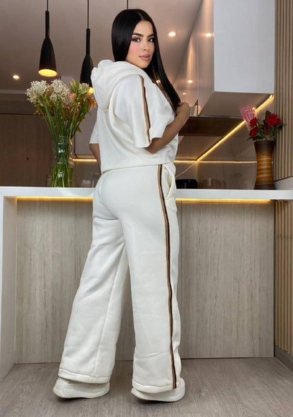 Mujer con conjunto de sudadera blanco con líneas marrones en cocina moderna